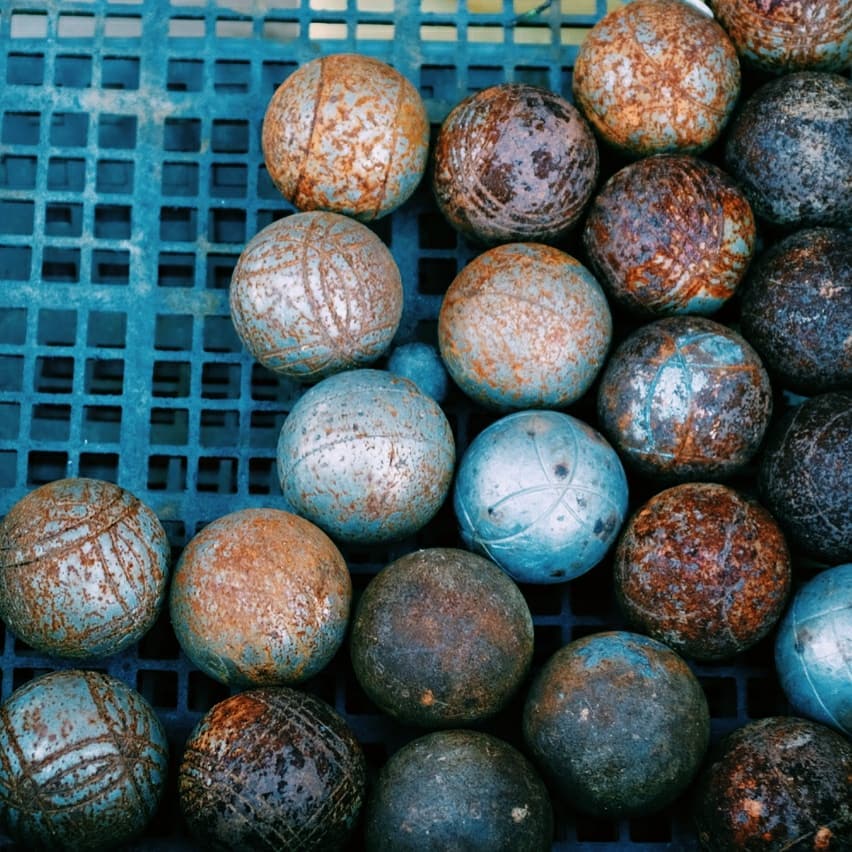 dans le village de l'Herbe, un casier en plastique bleu rempli de boules de pétanques rouillées